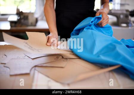 Fashion designer, patterns and fabric for clothes production, planning and measurements in workshop. Person hands with cardboard or shape of garment Stock Photo