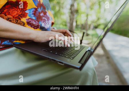 Office outdoors, close-up of female hands typing on keyboard with laptop Stock Photo