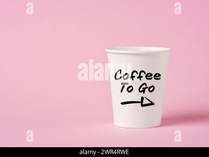 The word coffee to go on a paper coffee cup on pink background. Stock Photo