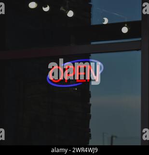 An 'open' sign displayed in a window Stock Photo