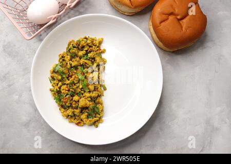 Anda Masala Bhurji or Spicy Indian scrambled eggs with bread or Bun Pav, a popular street food in Mumbai. Served in white plate along with copy space Stock Photo