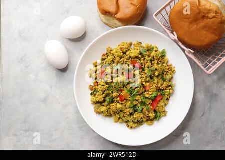 Anda Masala Bhurji or Spicy Indian scrambled eggs with bread or Bun Pav, a popular street food in Mumbai. Served in white plate along with copy space Stock Photo