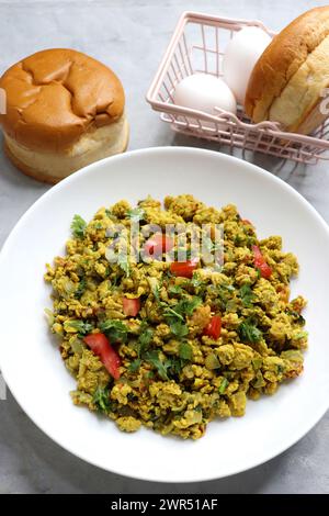 Anda Masala Bhurji or Spicy Indian scrambled eggs with bread or Bun Pav, a popular street food in Mumbai. Served in white plate along with copy space Stock Photo