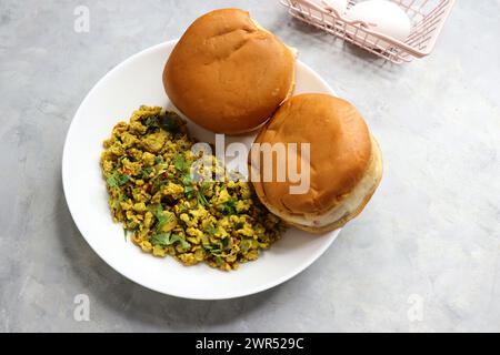 Anda Masala Bhurji or Spicy Indian scrambled eggs with bread or Bun Pav, a popular street food in Mumbai. Served in white plate along with copy space Stock Photo