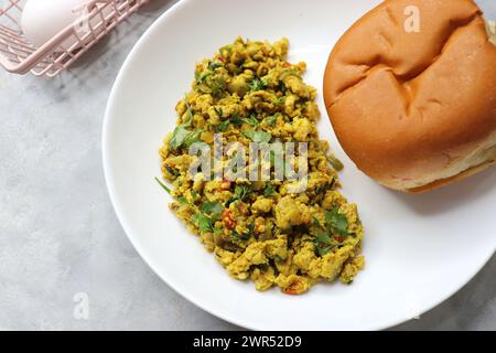 Anda Masala Bhurji or Spicy Indian scrambled eggs with bread or Bun Pav, a popular street food in Mumbai. Served in white plate along with copy space Stock Photo