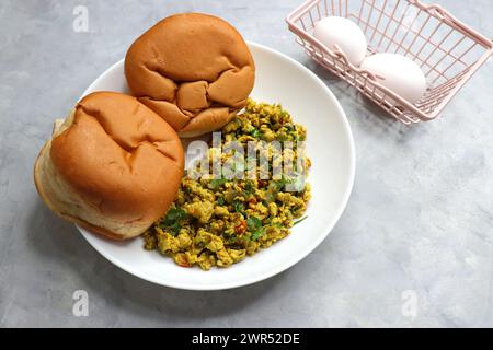 Anda Masala Bhurji or Spicy Indian scrambled eggs with bread or Bun Pav, a popular street food in Mumbai. Served in white plate along with copy space Stock Photo