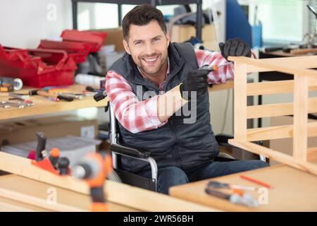 happy disabled worker in wheelchair in a carpenters workshop Stock Photo