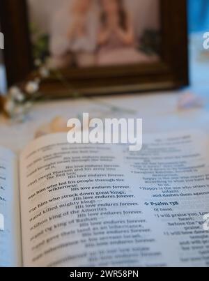 Opened bible on table showing verse on love in Book of Psalms, next to photo of a couple. Stock Photo