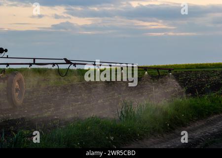 Tractor spraying pesticides on vegetable field with sprayer at spring. Stock Photo