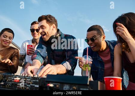 cheerful multiracial men and women dancing at rooftop party with DJ and drinking cocktails Stock Photo