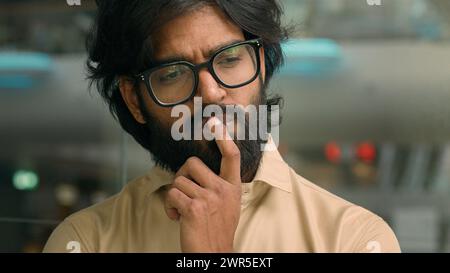 Thoughtful worried Arabian businessman thinking of future business challenges financial crisis. Doubtful serious pensive Indian bearded man in glasses Stock Photo