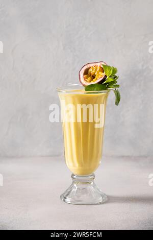 Passion Fruit and mango lassi in traditional tall glass on white background. Healthy beverage made of yogurt, water, fruits and ice. Vertical format. Stock Photo