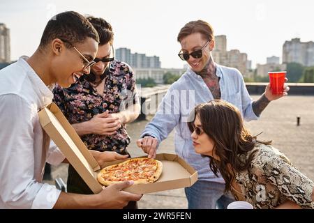 joyous interracial friends with stylish sunglasses sharing pizza and having fun at rooftop party Stock Photo