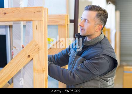 male worker stacking materials in wooden display frame Stock Photo
