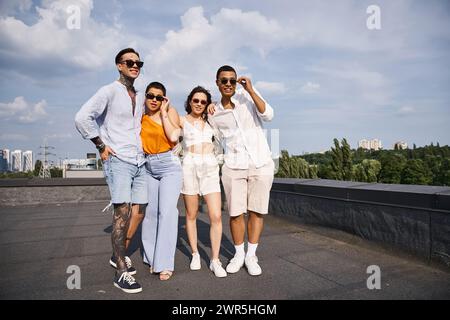 four multicultural jolly friends with modern sunglasses posing happily on rooftop together Stock Photo