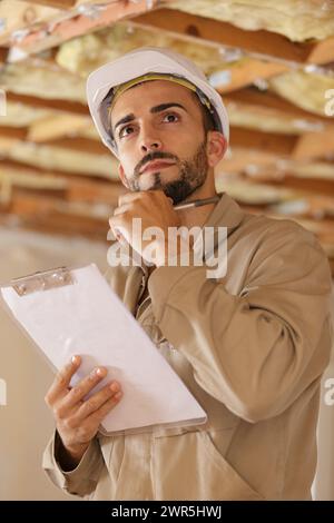 builder thinking about something while holding clipboard Stock Photo