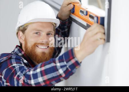 construction worker using bubble level while installing window indoors Stock Photo