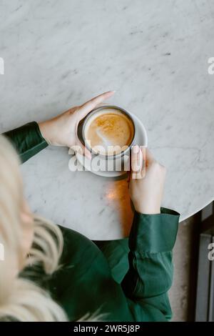Woman drinking coffee and working on laptop at coffee shop Stock Photo