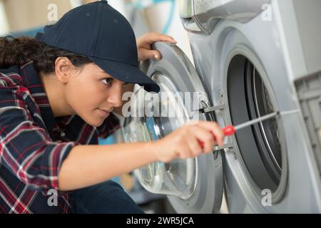 woman is using a screwdriver to fixing washing machine Stock Photo