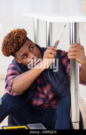 handsome young man using screwdriver for fixing table Stock Photo