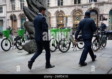 City workers walk past the sculpture entitled 'City Wing' and Lime rental bikes on Threadneedle Street in the City of London, the capital's financial district (aka the Square Mile), on 7th March 2024, in London, England. 'City Wing' is by the artist Christopher Le Brun. The ten-metre-tall bronze sculpture is by President of the Royal Academy of Arts, Christopher Le Brun, commissioned by Hammerson in 2009. It is called ‘The City Wing’ and has been cast by Morris Singer Art Founders, reputedly the oldest fine art foundry in the world. Stock Photo