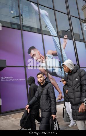 With months before the 2024 Paris Olympics, members of the public pass beneath a huge image of Team GB gymnast and previous Olympic gold medalist, Max Whitlock outside Coutts Bank on the Strand, on 7th March 2024, in London, England. Coutts Bank (and Natwest Bank) are currently Team GB's official corporate partners. Stock Photo