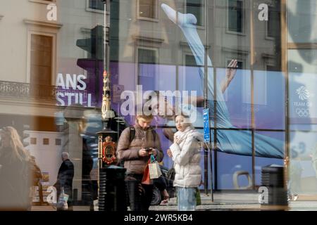 With months before the 2024 Paris Olympics, members of the public pass beneath a huge image of Team GB gymnast and previous Olympic gold medalist, Max Whitlock outside Coutts Bank on the Strand, on 8th March 2024, in London, England. Coutts Bank (and Natwest Bank) are currently Team GB's official corporate partners. Stock Photo