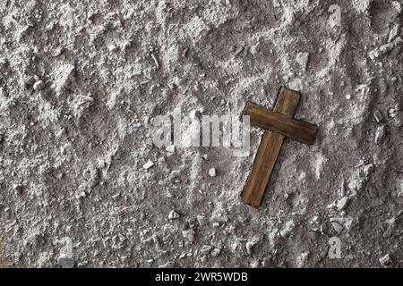 Religious background with wooden christian cross on ashes. Top view. Stock Photo