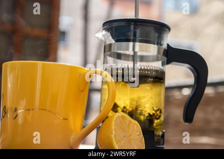 Teapot (French press) with half lemon and teapot at wooden table on the balcony, morning tea time, aromatic aromatherapy fresh and herbal, organic tea Stock Photo