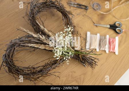 Wicker heart shaped wreath of birch branches and supplies for DIY making Stock Photo