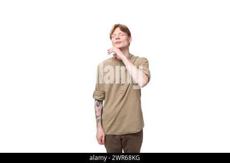 close-up of a young red-haired man in a beige shirt in the studio on a white background Stock Photo