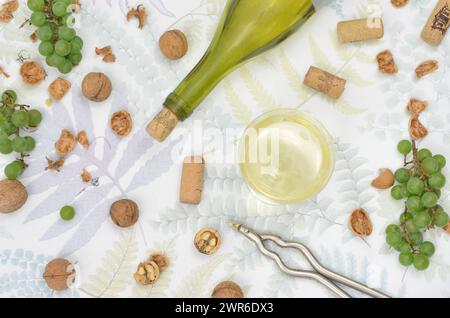 Wine in a glass, bottle, green grapes, nuts on a table, top view. Stock Photo