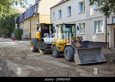 Bulldozer and roller for laying asphalt on a city street with removed pavement. Repair and construction site for road works Stock Photo