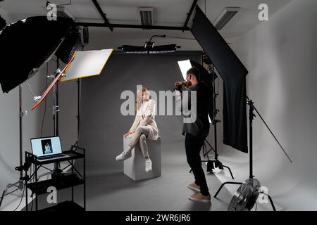 Model young woman preparing posing for photo taken with professional photographer in studio on fashion concept Stock Photo