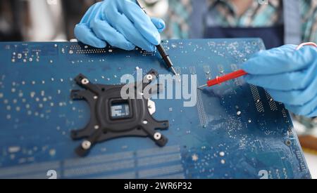Repairman diagnosing breakdown in computer motherboard using tester closeup Stock Photo