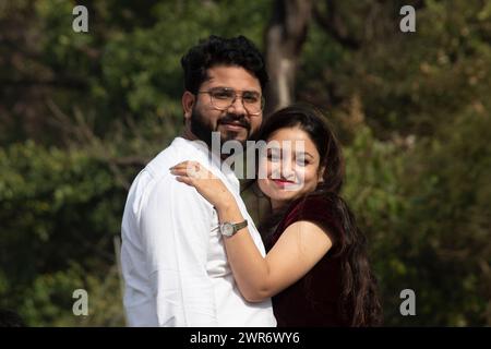 Joyful couple, sharing an embrace amidst the scenic beauty of Rishikesh, gazes happily into the camera against a backdrop of lush trees, Uttarakhand Stock Photo