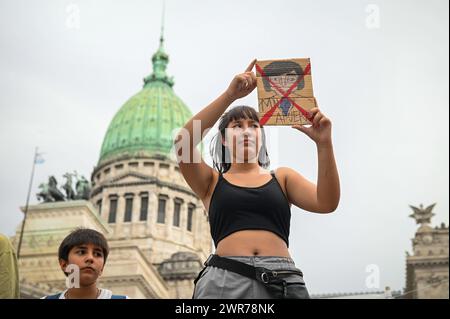 Buenos Aires, Argentina. 08th Mar, 2024. A young woman holds a drawing reading 'Milei out' in front of Congress on International Women's Day. The government of the new head of state, Milei, has banned the use of gender-sensitive language in all federal authorities. The former Ministry of Women, Gender and Diversity has been dissolved as such and is now under the new Ministry of Human Capital. Credit: Igor Wagner/dpa/Alamy Live News Stock Photo