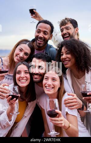Multiracial friends gathered together having fun in a barbecue, drinking wine and enjoying the day. Stock Photo
