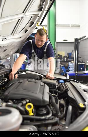 car mechanic in a workshop - engine repair and diagnosis on a vehicle Stock Photo