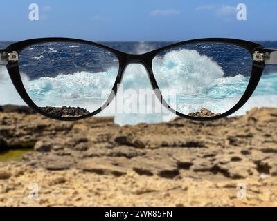 Landscape view of a coastal scene in focus through the lenses of a pair of glasses. Eyesight and focus concept. Stock Photo