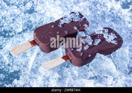 The Chocolate Coated Ice Cream Bars On Wooden Stick On The Chopped Ice Crystals. Stock Photo