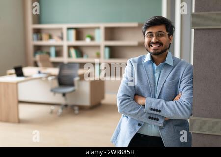 Confident successful Indian businessman stands crossing hands in modern office Stock Photo