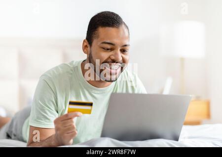 Relaxed african american man using laptop and credit card Stock Photo