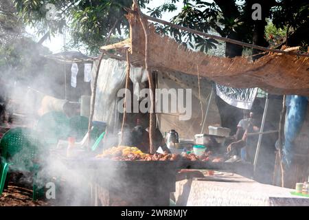 Food vendors are engulfed in smoke as they prepare food by the roadside in Senga Bay, Salima. The vendors were selling to revellers who were attending a music festival. Malawi. Stock Photo