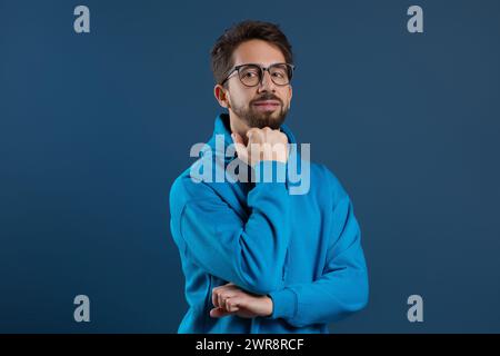 Pensive man wearing eyeglasses resting chin on hand and looking at camera Stock Photo