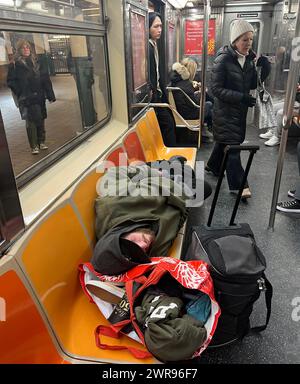 Man with luggage sprawled out across subway train seats sleeping on the F line in Manhattan. Stock Photo