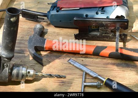 A chisel, a hammer, a drill and a jigsaw are a carpenter's tool on the table, close-up. Stock Photo