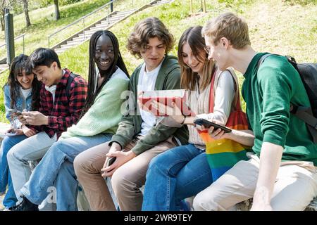 Group of young friends viewing tablet outdoors - connection and learning - Teenage students interacting with digital screens Stock Photo