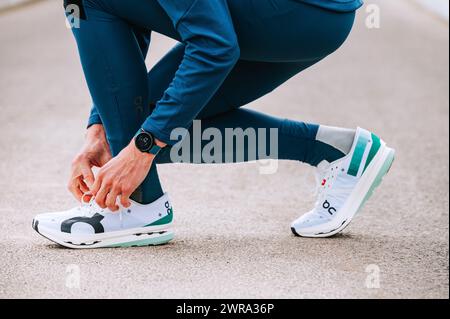 GENEVA, SWITZERLAND, MARCH 10. 2023: On Cloudboom Echo 3, On super shoes, a marathon runner ties his shoes on the road before race. Stock Photo