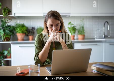Focused thoughtful woman with laptop deep in process of solving tasks problems remote work IT field. Stock Photo